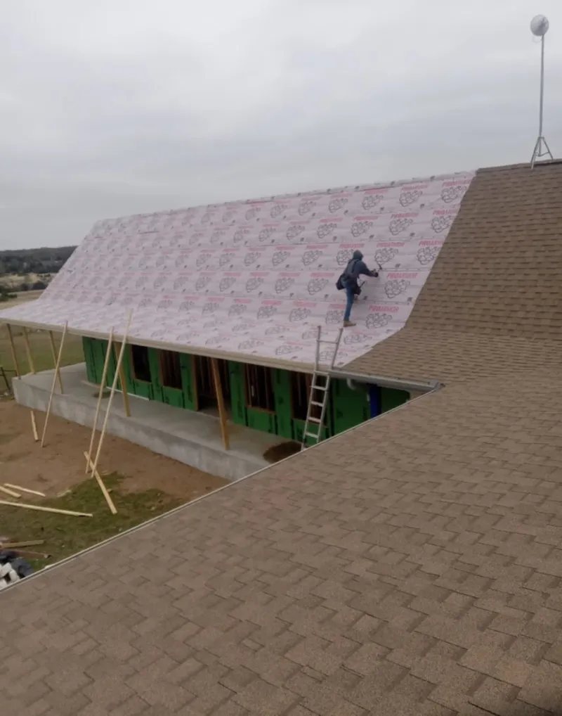 Worker preparing underlayment for a metal roof installation in California